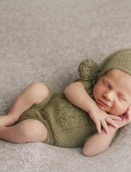 El mono y gorro con pompón para una sesión de fotos para recién nacidos